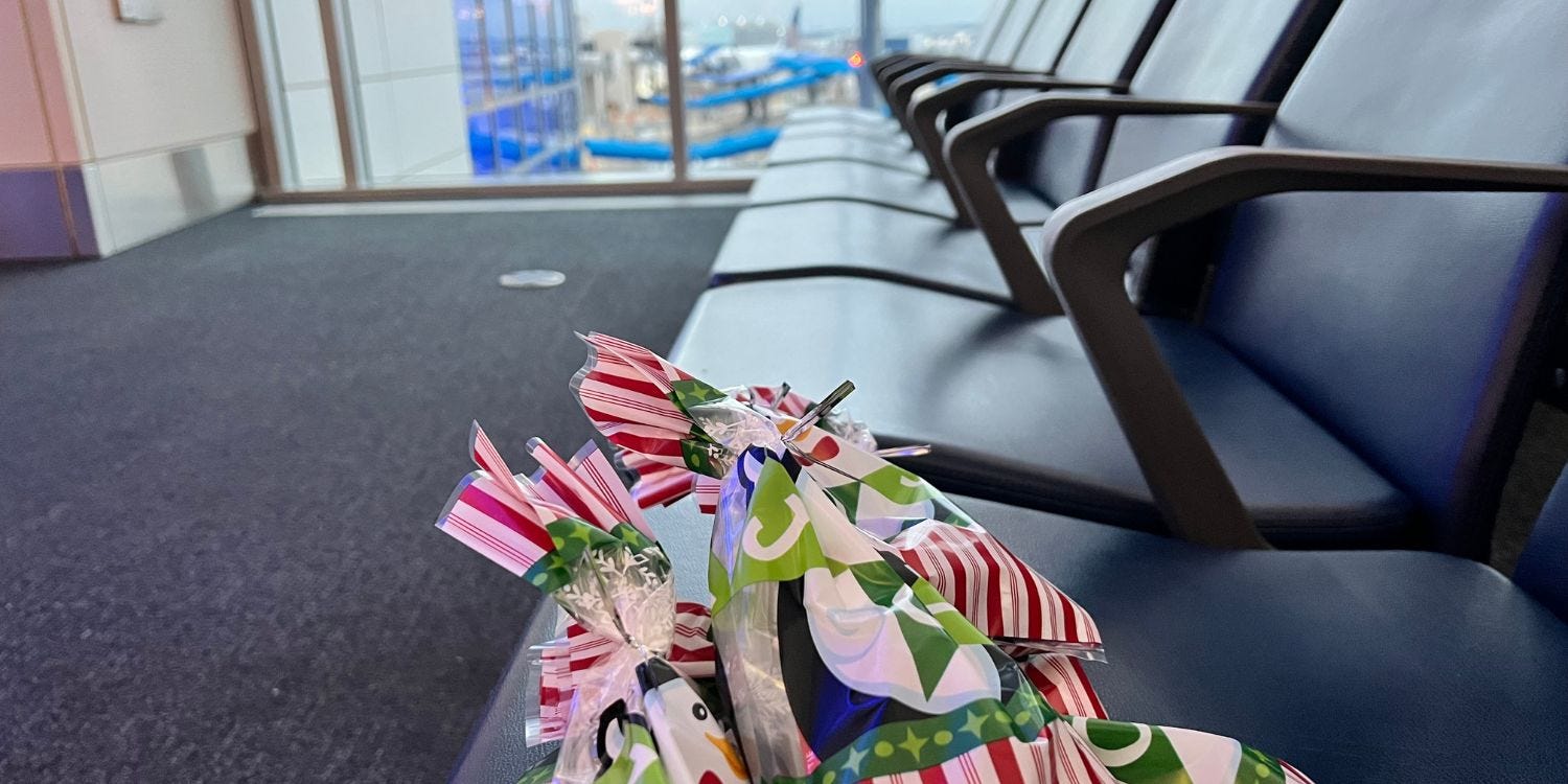 Picture of treat bags on a seat in an airport, looking out at the tarmac.